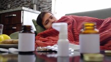 Ginger, Lemon, Onion And Different Drugs On Table On Background Sick Man. Alternative Remedies And Traditional Pills To Treat Colds And Flu. Sick Man Wrapped In Red Blanket In Background