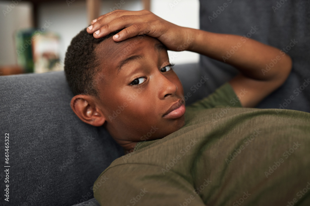 Indoor closeup image of bored lazy black kid boy lying on sofa with ...