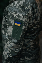 Ukrainian soldier in military uniform with the national flag on his shoulder. Dramatic background, cold colors. Concept of war and peace, conflict between Ukraine and Russia