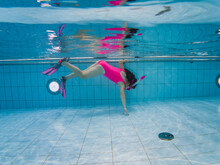 Underwater. A Kid, Girl In A Pink Swimsuit With A Snorkel, Mask And Diving Fins Swims In The Pool Underwater.