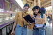 © Songsak C - Two Asian female tourists are checking their travel plans on a tablet after getting off a train.