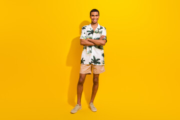 Wall Mural - Full body photo of attractive young man folded arms confident dressed stylish palms print clothes isolated on yellow color background
