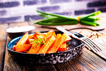 Canvas Print - Fried carrots with green herbs in baking tray, close up