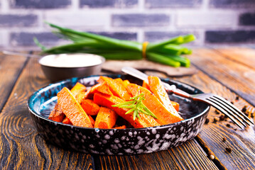 Canvas Print - Fried carrots with green herbs in baking tray, close up