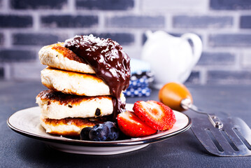 Canvas Print - Traditional syrniki served with fresh strawberries, blueberry, mint leaves, drizzled with chocolate