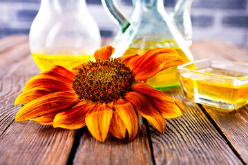 Wall Mural - Organic sunflower oil in a small glass jar with sunflower seeds and fresh flowers. Outdoors