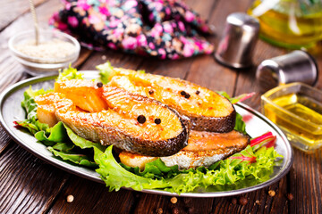 Wall Mural - Fried salmon steak with spice and vegetables on wooden table