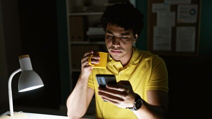 Poster - Young latin man business worker using smartphone drinking coffee at the office