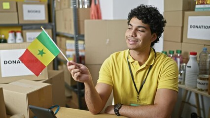 Wall Mural - Young latin man volunteer holding senegal flag smiling at charity center