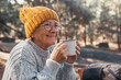 © Daniel - Head shot portrait close up of middle age woman relaxing drinking coffee or tea sitting at table in the forest of mountain in the middle of nature. Autumn season enjoying concept lifestyle..