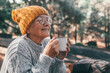 © Daniel - Head shot portrait close up of middle age woman relaxing drinking coffee or tea sitting at table in the forest of mountain in the middle of nature. Autumn season enjoying concept lifestyle..