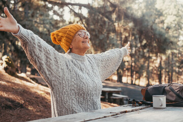 Canvas Print - Head shot portrait close up of middle age woman enjoying and relaxing sitting at table in the nature in the forest of mountain. Old female person opening arms and closing eyes feeling free. Freedom 