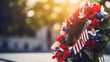 A red, white, and blue wreath placed at the base of a statue honoring fallen soldiers, with copy space, blurred background