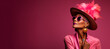 Portrait of a fashionable woman wearing an expressive hat, isolated against a vibrant pink background 