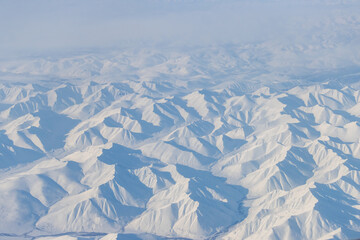 Wall Mural - aerial view of snow-capped mountains. winter snowy mountain landscape. travel to the far north of ru