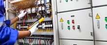Electricity And Electrical Maintenance Service. Engineer Hand Checking Electric Current Voltage At Circuit Breaker Terminal And Cable Wiring In Main Power Distribution Board AHU Starter Control Panel.