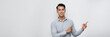 © makistock - smiling young handsome Asian man pointing fingers in empty space aside