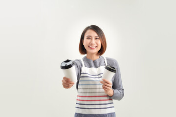 young woman in apron holds two takeaway paper cup isolated over white background