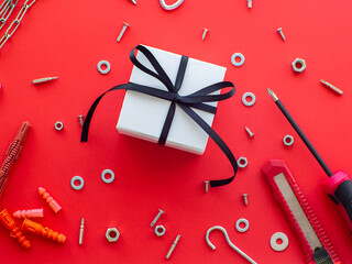 Construction tools and wrapped gift on red background. Construction greeting card for Christmas, Fathers, Mens or Valentines day. Repair home with love. Gifts for lover. Buying presents for man.