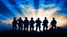 Eight Military Silhouettes Against The Background Of A Sunset Sky In Blue And The Rays Of The Sun With Copy Space. Military Service Concept