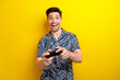 Portrait of astonished cheerful person good mood hands hold controller playing video games isolated on yellow color background