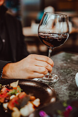 Sticker - man hand holding a glass with red wine in a restaurant