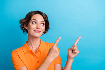 Wall Mural - Photo of dreamy charming girl dressed orange polo showing two fingers looking empty space isolated blue color background