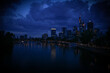 the skyline in frankfurt am main at night. panorama picture from a bridge over a big river. main promenade and an excursion boat in the evening light