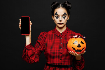 Wall Mural - Young woman with Halloween makeup face art mask wear clown costume red dress hold Jack-o-Lantern carved pumpkin mobie cell phone isolated on plain solid black background. Scary holiday party concept.