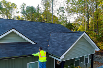 Is worker cleaning clogged roof gutter drain from dirt, debris, fallen leaves