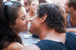 © Marine G/peopleimages.com - Smile, couple and kiss at cafe with friends for bonding, love and weekend fun. Happy, affection and young man and woman with care, together and romance at an outdoor restaurant with a group of people