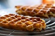 © Joeri - A portrait of some delicious and tasty Belgian waffles lying on a round cooling rack, ready to be eaten with somekind of topping like powder sugar or whipped cream.
