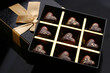 Heart shaped painted luxury handmade bonbons in a gift box on a black background. Chocolates for Valentine's Day.