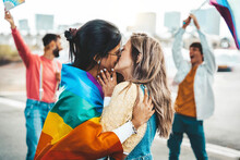 Diverse Group Of Young People Celebrating Gay Pride Festival Day - Lgbt Community Concept With Two Girls Kissing Outdoors - Multiracial Trendy Friends Standing On A Yellow Background