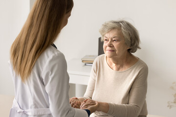 older woman visit to doctor for medical checkup in hospital. caring young therapist in white uniform