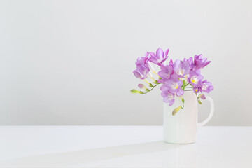 Wall Mural - purple freesia in glass vase on white background