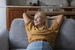 © fizkes - Relaxed peaceful middle aged 50s woman resting on comfortable couch, leaning on back, breathing fresh air, looking at window away, thinking, dreaming, smiling, enjoying home leisure, break