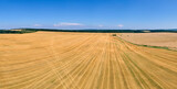 Fototapeta Krajobraz - Aerial landscape view of yellow cultivated agricultural field with dry straw of cut down wheat after harvesting