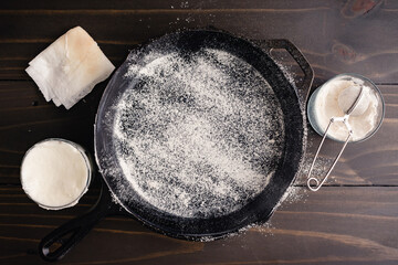 Canvas Print - Greased and Floured Cast-Iron Skillet: Frying pan coated with vegetable oil and dusted with all-purpose flour to prevent sticking