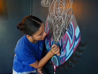 Woman drawing a picture on the wall with a brush. Beautiful model woman making artistic drawing on the wall