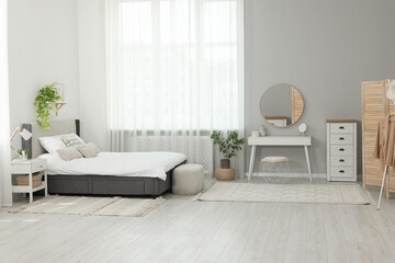 Poster - Stylish bedroom interior with large comfortable bed and ottoman near window