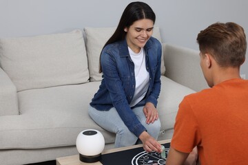 Astrologer predicting client's future with zodiac wheel, stones and crystals at wooden table indoors