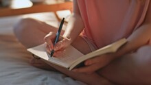 Teenage girl writing diary in sunlight closeup. Hands holding pen noting in book
