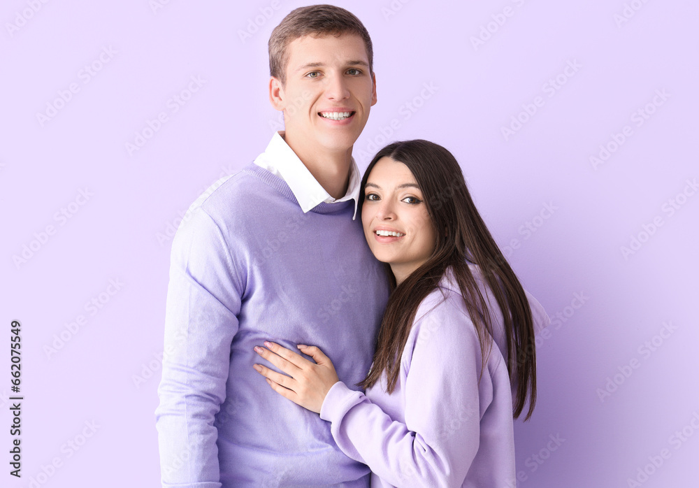 Happy young couple hugging on lilac background