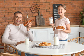 Canvas Print - Little girl with her father sitting at table and drinking milk in kitchen