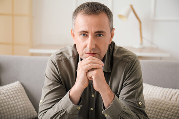 Poster - Handsome mature man sitting on grey sofa in living room