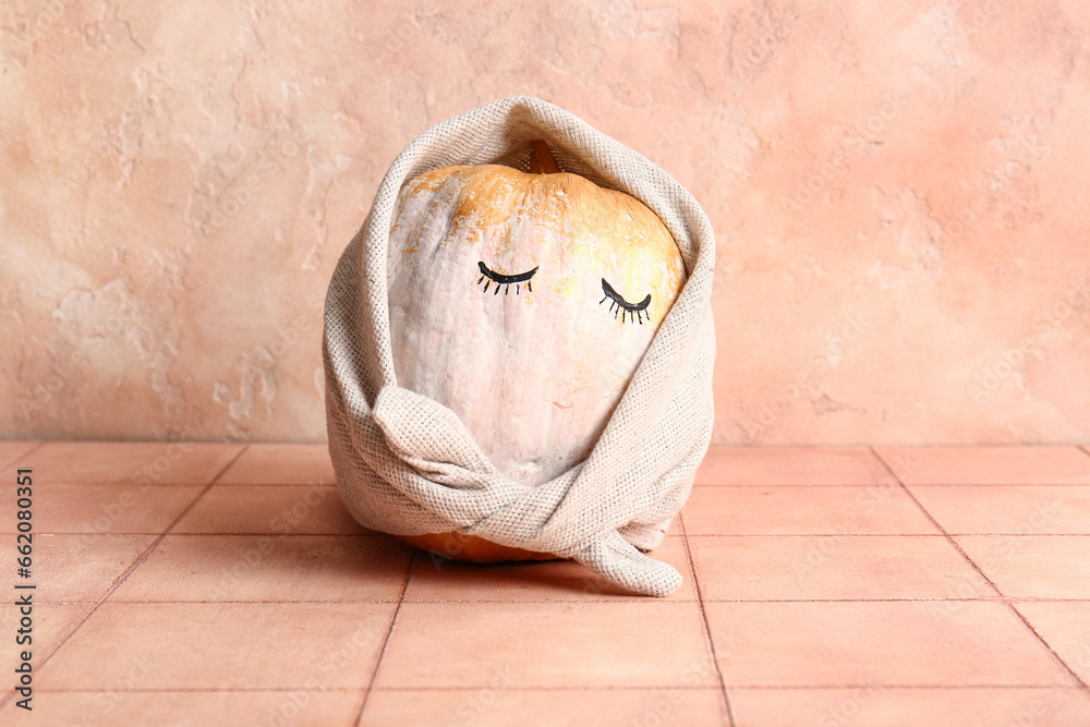 Painted Halloween pumpkin with eyes and towel on beige tiled table