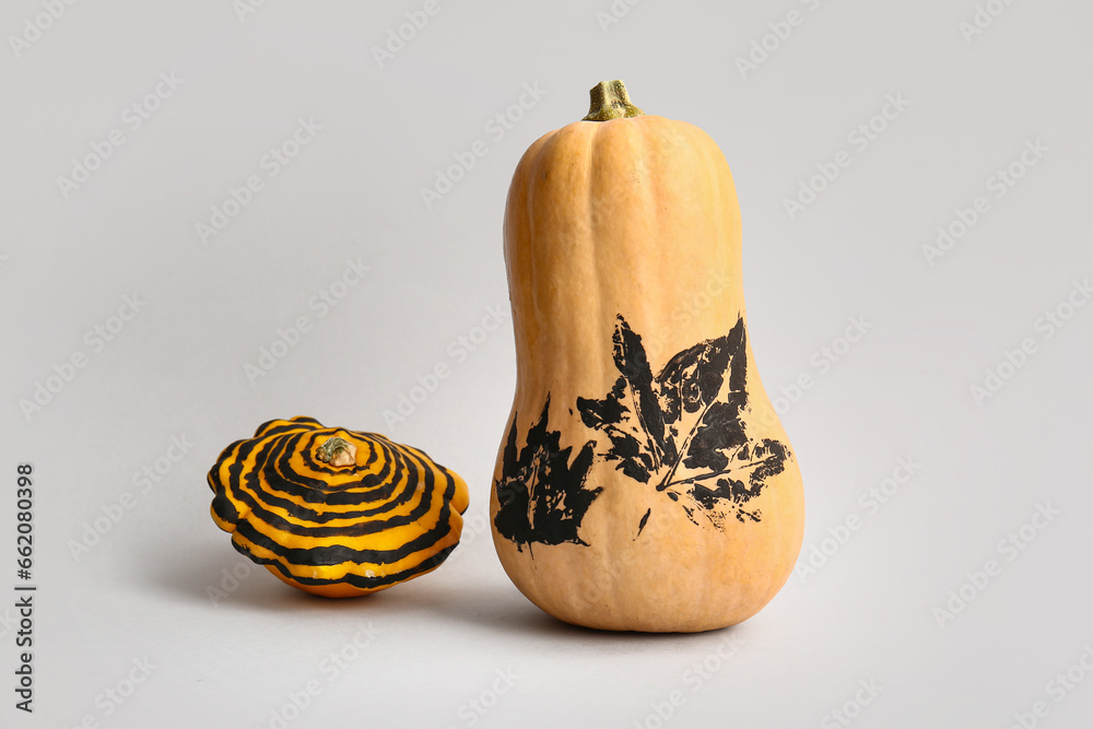 Painted Halloween pumpkins with autumn leaves and stripes on grey background
