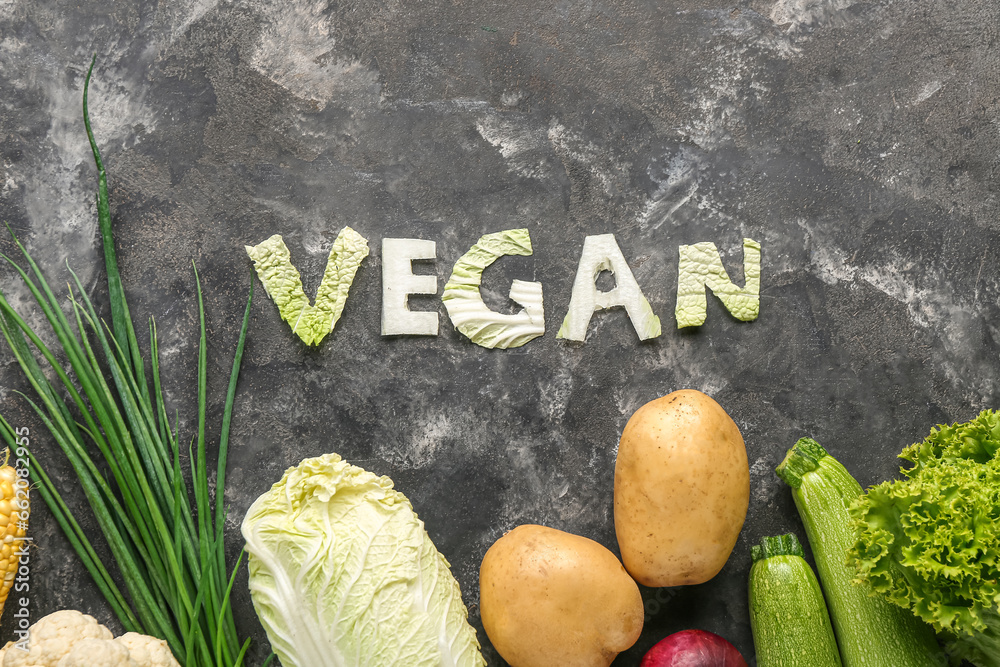 Word VEGAN made of cabbage and different fresh vegetables on black background
