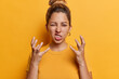 © wayhome.studio  - Photo of irritated angry young European woman gestures angrily and clenches teeth expresses anger wears casual t shirt poses against vivid yellow background. Negative human emotions concept.